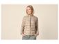 Femme portant une doudoune beige et un pantalon vert, les mains dans les poches.