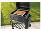 Une pizza sur une pierre à pizza dans un barbecue noir.
