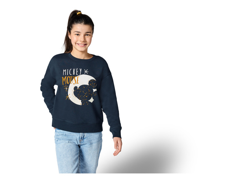 Une fille porte un sweat-shirt bleu avec un imprimé Mickey Mouse.
