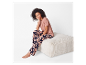 Modèle portant un pyjama fleuri et un t-shirt rose assis sur un pouf.