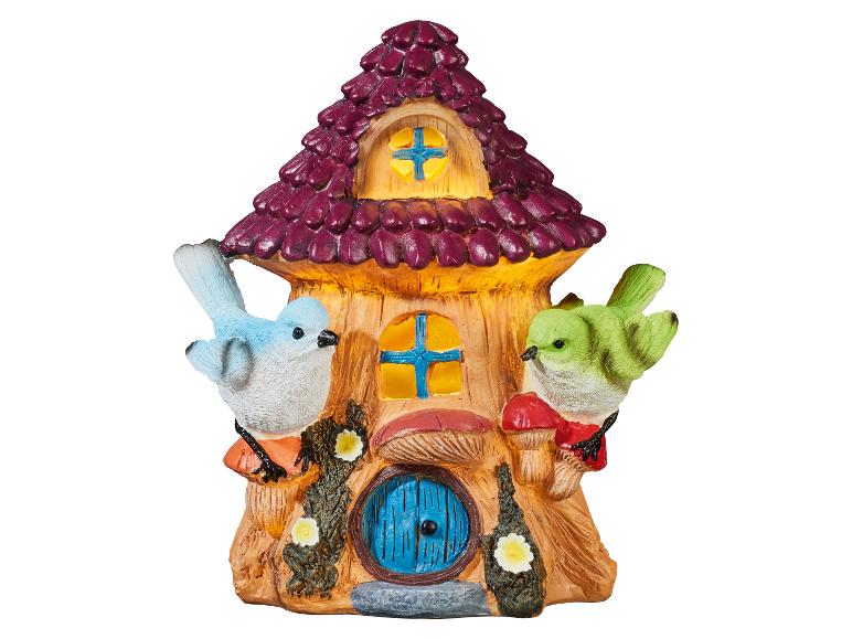 Maison de fée décorative avec deux oiseaux, des champignons et des fleurs, toit violet et fenêtres jaunes.