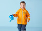 Un garçon porte un imperméable jaune avec une ancre et tient un arrosoir.