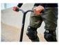 Une personne utilisant une trottinette freestyle noire avec des genouillères Hudora.