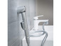 Une pomme de douche chromée avec un tuyau et un robinet blanc dans une salle de bain.