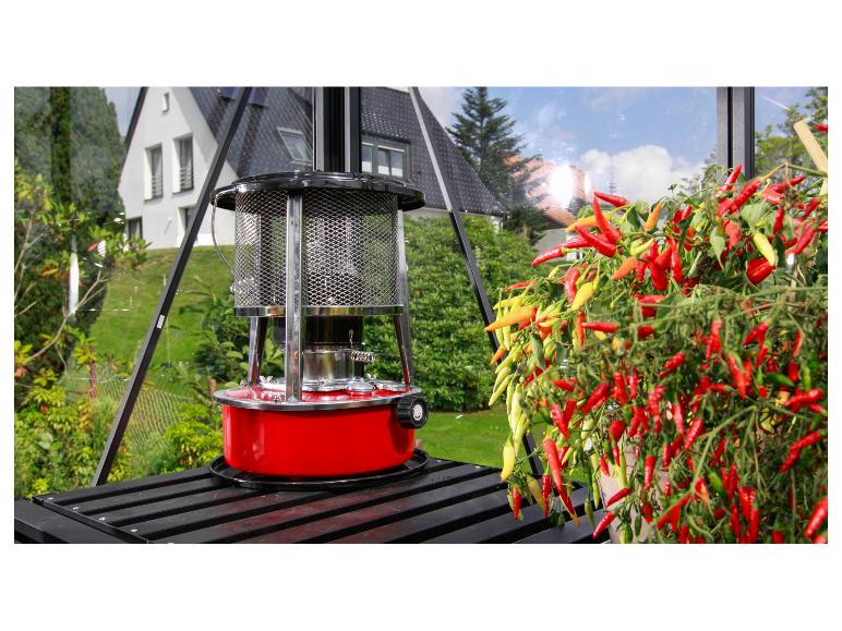 Chauffage de serre rouge à côté d'un plant de piment vibrant dans une serre.