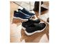 Des baskets slip-on noires et bleues sur un sol en bois.