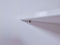 Une étagère blanche fixée à un mur blanc avec une vis.