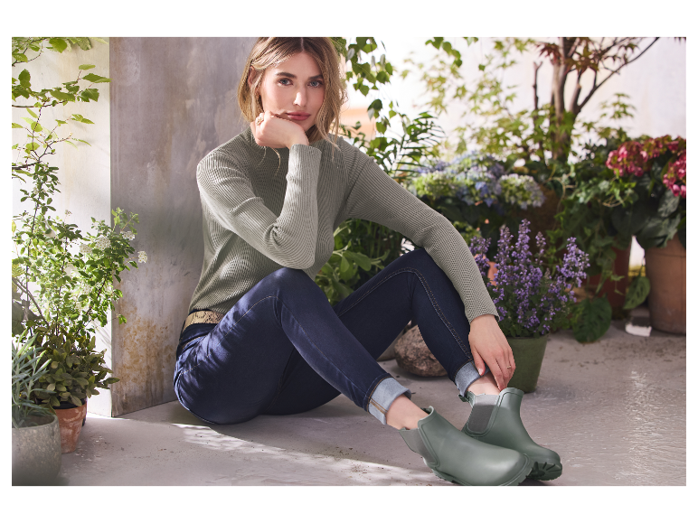 Modèle portant un pull en maille et un jean, arborant des bottes Hunter vert olive.