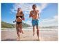 Couple courant sur la plage en maillots de bain.