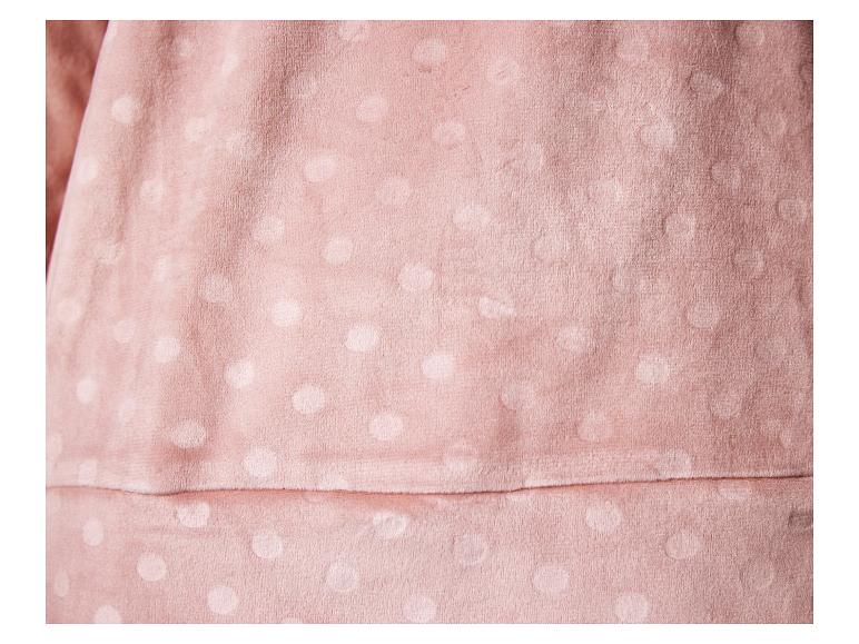 Gros plan d'un tissu rose doux avec un motif subtil à pois.