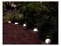 Lampes solaires en forme de galets éclairant un jardin.