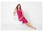 Femme en robe côtelée fuchsia sans manches et sandales beiges, assise sur une chaise blanche.