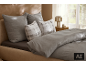 Lit avec oreillers et couette gris, et deux coussins décoratifs à carreaux.