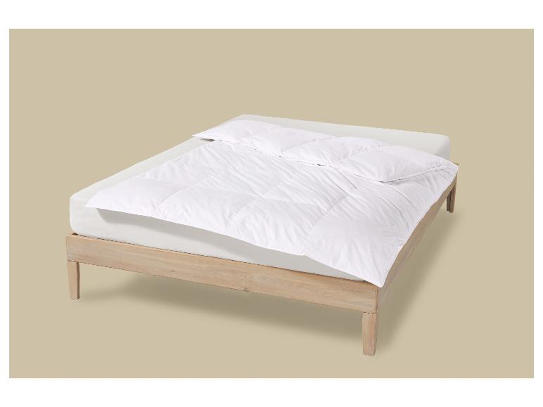 Lit en bois clair avec matelas blanc et couette blanche.