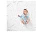 Bébé souriant sur un plaid blanc portant un body bleu clair à motif glands.