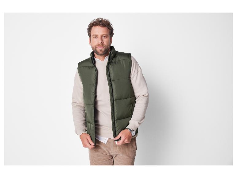 Un homme portant un gilet matelassé vert et un pull beige.