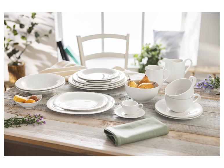 Vaisselle blanche en porcelaine sur une table en bois rustique, avec des fruits et des fleurs.