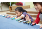Deux enfants jouent avec des petites voitures colorées sur une table bleue.
