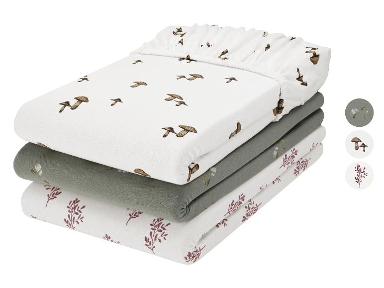 Trois draps-housses pliés avec motifs de champignons et plantes en blanc, vert et bordeaux.