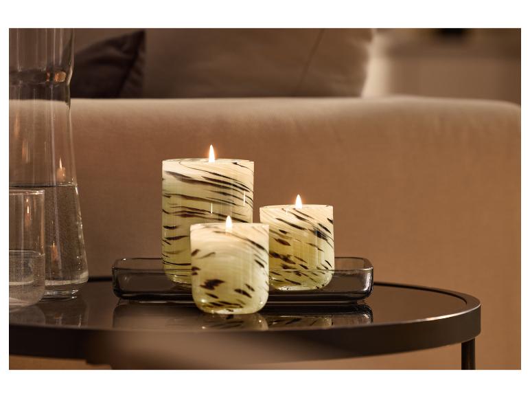 Trois bougies décoratives à motif zébré et une carafe en verre sur une table d'appoint.