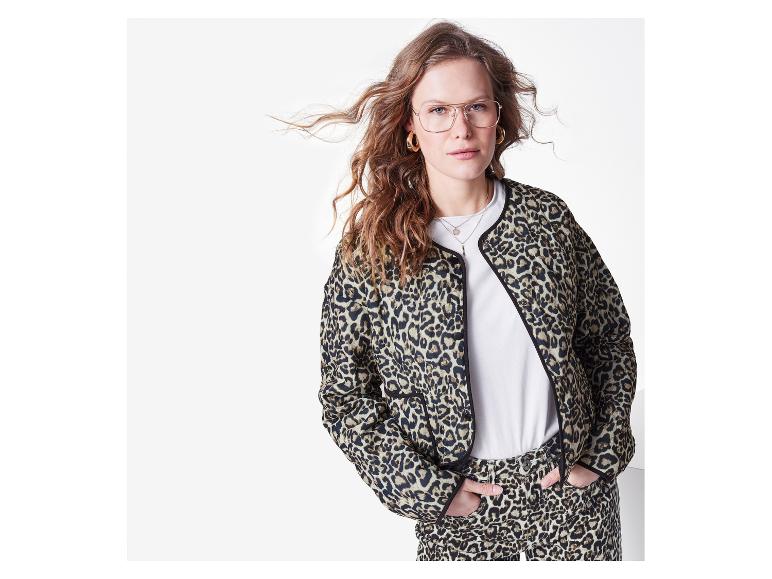 Femme portant une veste et un pantalon imprimé léopard, un t-shirt blanc et des lunettes.