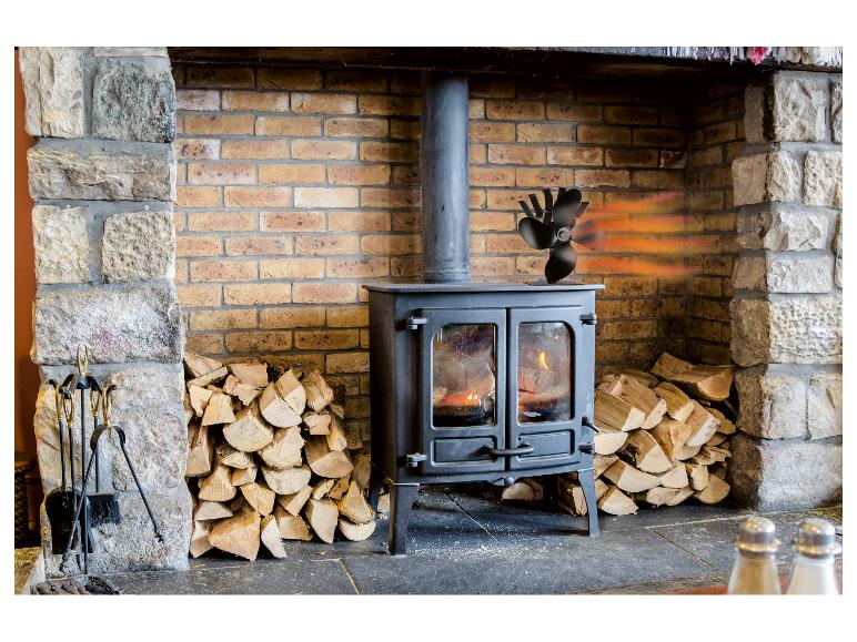 Poêle à bois avec ventilateur, bois de chauffage et outils de cheminée.