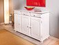 Un buffet en bois blanc avec trois portes et trois tiroirs.