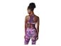 Femme de dos en brassière de sport violette et leggings à motifs.