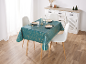 Table à manger avec une nappe sarcelle à étoiles dorées, dressée avec assiettes, verres et couverts.