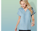 Une femme porte une chemise en jean bleu clair à manches courtes.