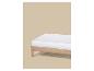 Matelas blanc sur un cadre de lit en bois sur fond beige.
