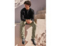Homme en sweat-shirt noir et pantalon vert avec des baskets noires.