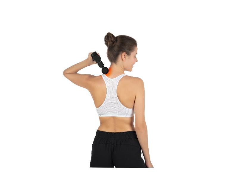 Une femme vêtue de vêtements de sport utilise un pistolet de massage sur son épaule.
