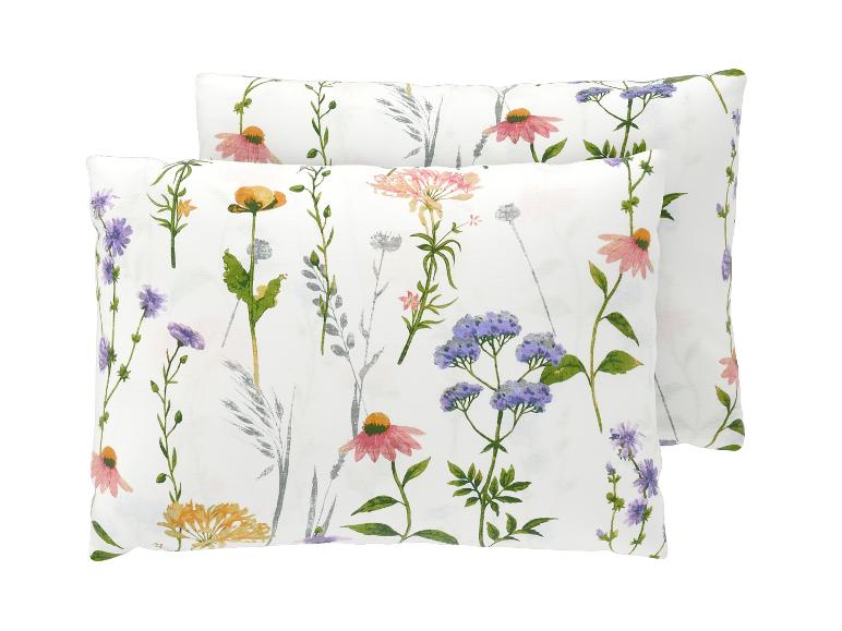 Deux oreillers blancs avec un motif floral aquarelle vif représentant diverses fleurs sauvages.