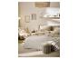 Chambre avec lit, literie beige, oreillers décoratifs et table d'appoint avec un livre.