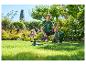 Homme dans un jardin avec un tuyau d'arrosage et un arroseur, arrosant la pelouse.