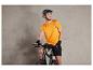 Un homme portant un casque de vélo et un t-shirt orange avec l'inscription 'Bike', assis sur un vélo noir.
