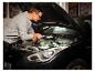 Homme avec lampe de travail »The Mechanic« inspectant le moteur de voiture.