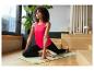 Femme en position de yoga sur un tapis, portant un débardeur rose et un legging noir.