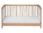 Un lit bébé en bois avec un matelas blanc.