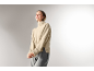 Une femme en col roulé beige et pantalon gris.
