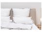 Oreillers et couette blancs avec étiquettes Fjödur sur un lit avec tête de lit beige.
