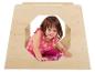 Une petite fille en robe rose est assise dans une maison de jeu en bois.