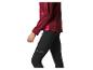Femme en veste de sport bordeaux et leggings noirs avec des détails réfléchissants.