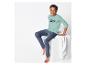 Un garçon portant un pantalon de pyjama bleu et un t-shirt vert clair avec l'inscription 'Future'.