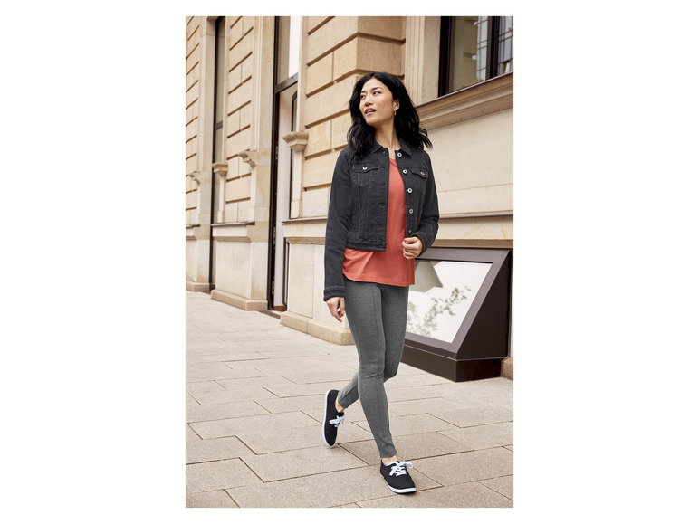 Une femme porte une veste en jean, un t-shirt et des leggings.