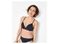Femme souriante en soutien-gorge et culotte noirs avec détails en dentelle.