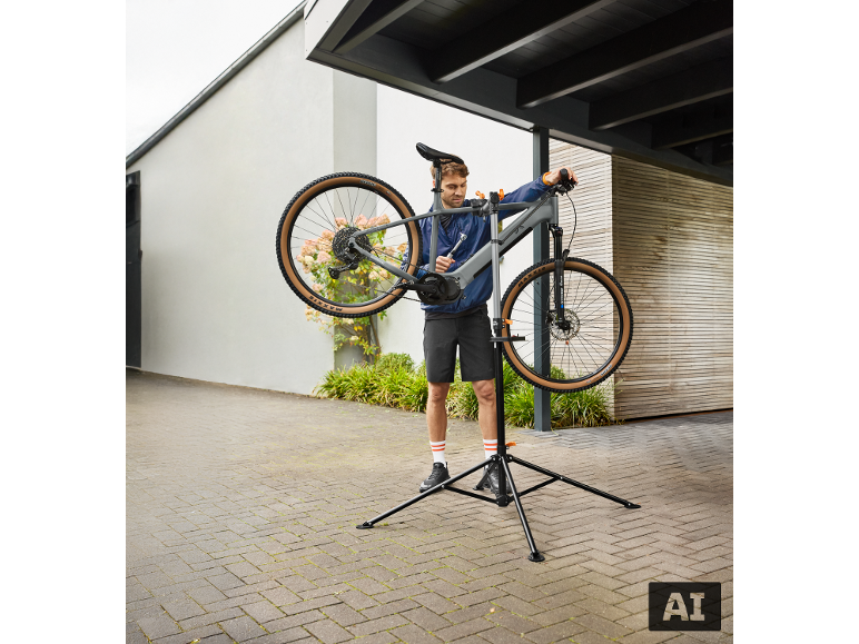 Un homme répare un vélo sur un support de réparation de vélo à l'extérieur.
