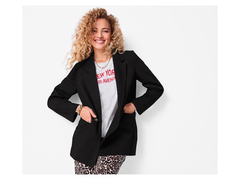 Femme souriante portant un blazer noir et un pantalon léopard.