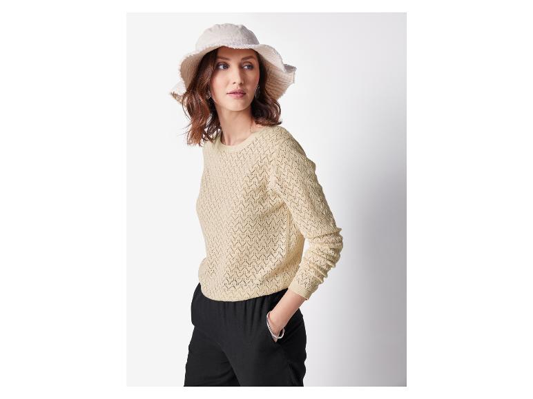 Femme en pull beige tricoté et chapeau clair.